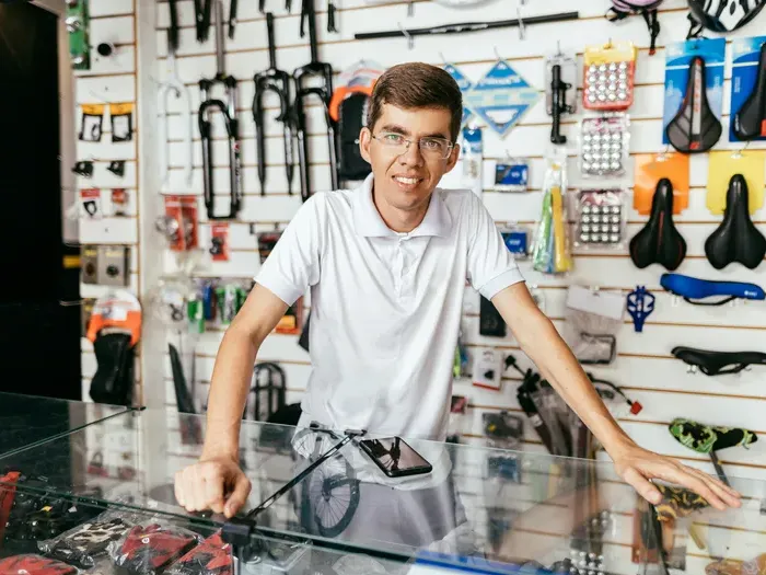 Shop owner at a bicycle parts counter, showing how CityBiz Now helps manage and promote a local business listing